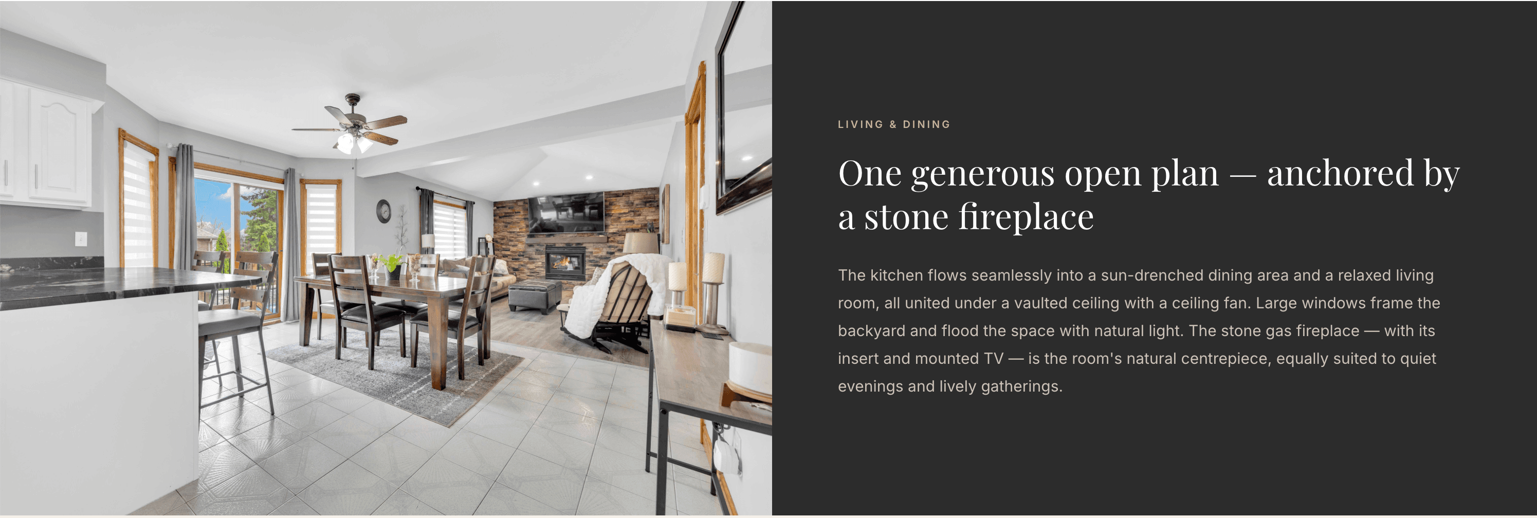 Open-plan kitchen, dining, and living area anchored by a stone fireplace